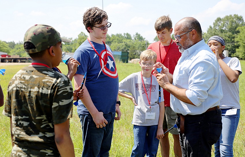 East Mississippi Community College Board of Trustees member Greg Stewart, at right, who also works for Aurora Flight Sciences, shows students enrolled in EMCC’s Camp AMP how to prepare rockets for launch. 