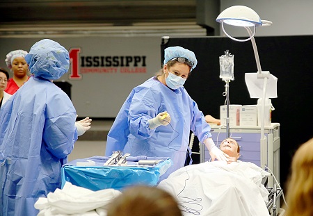 East Mississippi Community College Associate Degree Nursing instructor Karen Taylor, at right, plays the role of surgeon during a medical emergency simulation at the college's Golden Triangle campus in which students from all Division of Nursing and Allied Health programs participated.