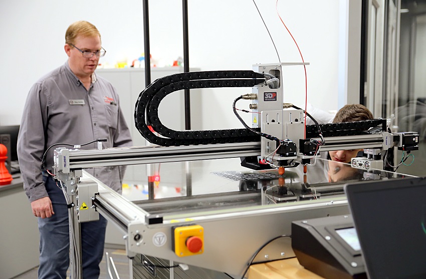 East Mississippi Community College’s Engineering Technology, Drafting & Design program now has an industrial-grade 3D printer to train students in additive manufacturing. Here, program instructor Ray Hollis, at left, and student Max Pyron watch as the machine starts a print job. 