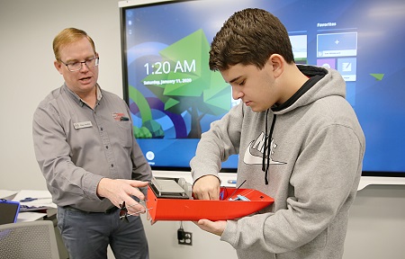 East Mississippi Community College Engineering Technology, Drafting & Design student Max Pyron of Ackerman, at right, examines a boat he and his classmates are working on for an assignment while program instructor Ray Hollis looks on. The boat was constructed with small 3D printers used to teach students additive manufacturing. The program now has a large, professional-grade 3D printer like those found in industry that will enable students to work on larger projects. 