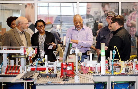 Mechatronics Technology instructor Ben Harris, far right, talks to visitors during an Oct. 18, 2019 grand opening ceremony for EMCC’s Communiversity. Here, he shows them a miniature assembly line used for training purposes that mimics larger automated assembly lines found in many modern manufacturing plants.