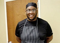 Former Lions football standout Derrick “DJ” Wilson, center, holds off a Gulf Coast Community College defender in this file photo from the 2011 season in which the Lions were undefeated and claimed a national championship. Wilson now owns a food catering business.