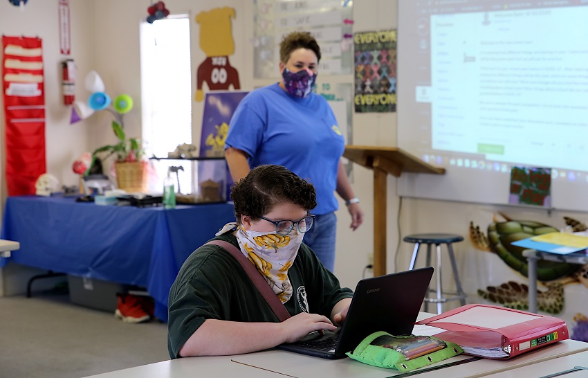 Golden Triangle Early College High School junior Sarah Clark works on an assignment while biology teacher Brandy Burnett, at back, looks on. The fall term at GTECHS began Aug. 10 and some students returned for in-class instruction while others are taking virtual classes online.