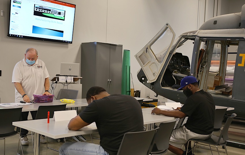 EMCC Workforce Trainer Carey Butler, at left, works with students in the Manufacturing Skills, Composite and Assembly course tailored to provide the skills needed by employees with Aurora Flight Sciences, a Boeing Company.