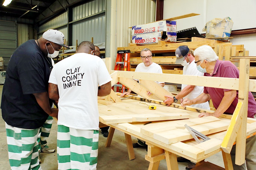 East Mississippi Community College Construction Skills instructor Johnny Duren, at right, watches as inmates from the Clay County Detention Center, who are enrolled in the program, frame a roof during class. 