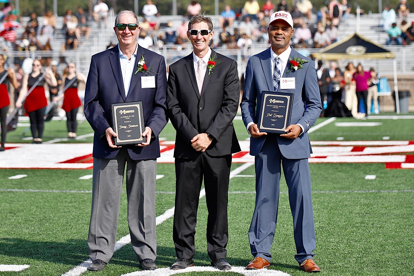 EMCC President Dr. Scott Alsobrooks, center, presents Tommy Tomlinson, at left, with the 2023 Alumnus of the Year Award, and Pat Granger, at right, with the 2023 Distinguished Service Award during halftime of the college’s Oct. 21 Homecoming football game.