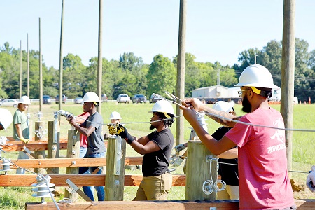 Students enrolled in the new Utility Lineworker Technology program on East Mississippi Community College’s Golden Triangle campus perform outdoor lab work. The utility poles in the background will be used to instruct the students on pole climbing. 