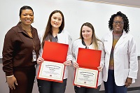 East Mississippi Community College Associate Degree Nursing students Macy Minor, second from left, and Alyssa Franks, third from left, are presented certificates for providing medical assistance at the scene of an automobile accident, by EMCC Director of Nursing Programs/Associate Dean of Health Sciences Jamonicia Johnson, at right, and Associate Degree Nursing Division Chair Dr. Eljenette West, at left.